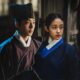 Homem e mulher, em hanbok, divididos por linha irregular, com fundo escuro e textura