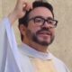 Padre Fábio de Melo de óculos, barba e veste sacerdotal branca, mão na cabeça