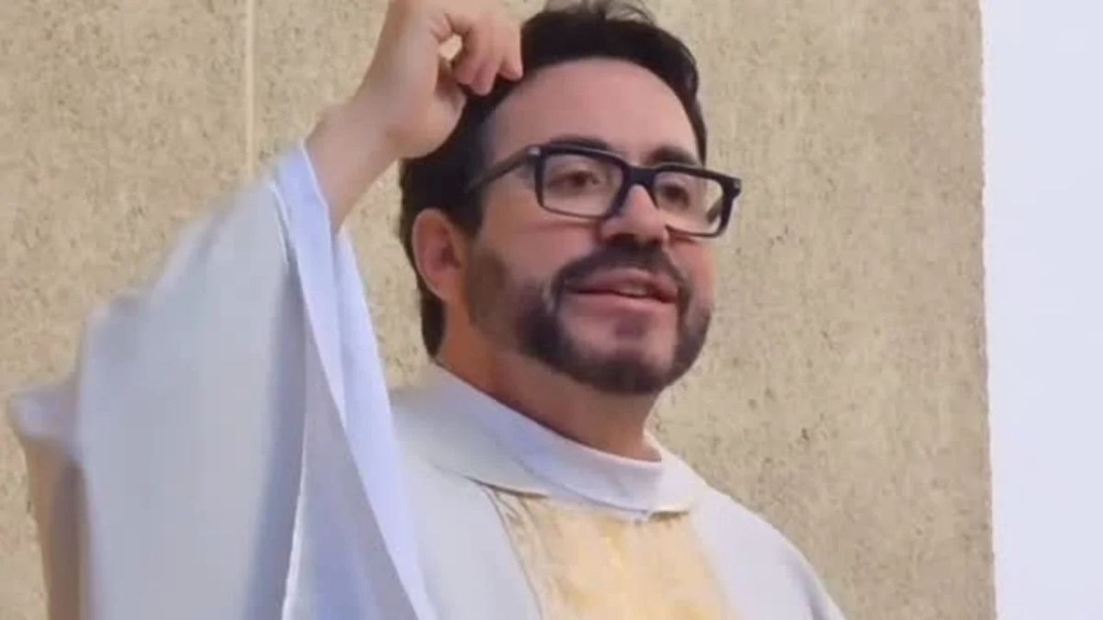 Padre Fábio de Melo de óculos, barba e veste sacerdotal branca, mão na cabeça