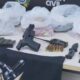 Mesa com pistola, carregadores, munições, rádio, faca, coldre, notas e sacolas plásticas