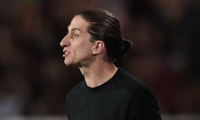 Homem de perfil cabelo longo preso camiseta preta com boca semiaberta
