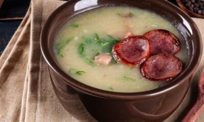 Tigela de caldo verde com linguiça calabresa fatiada, couve e pedaços de carne