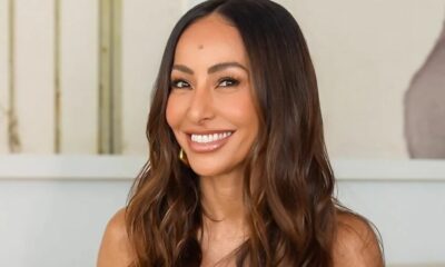 Sabrina Sato sorrindo amplamente, com cabelo castanho ondulado e brinco dourado