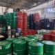 Armazém com pilhas de tambores verdes, vermelhos e pretos, além de galões e embalagens diversas