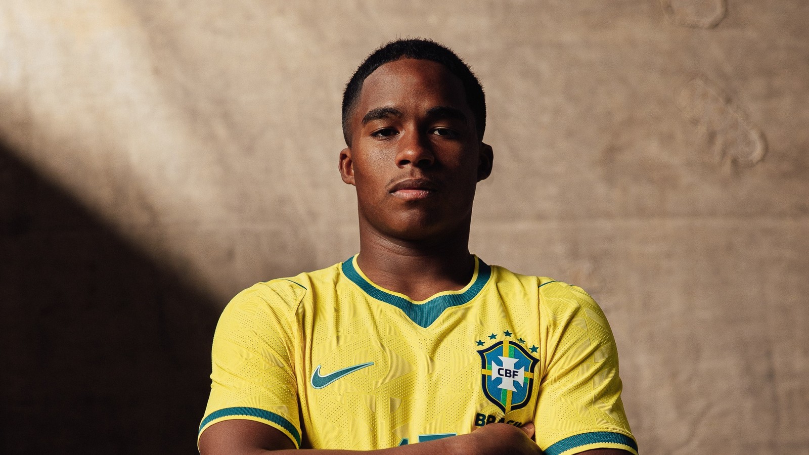 Endrick em camisa amarela da Seleção Brasileira com logotipos CBF e Nike, braços cruzados