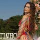 Mel Maia com roupa de crochê colorida, ao ar livre, com placa 18TINHO