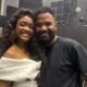 Erika Januza e Arlindinho sorrindo e abraçados em um estúdio com fundo escuro