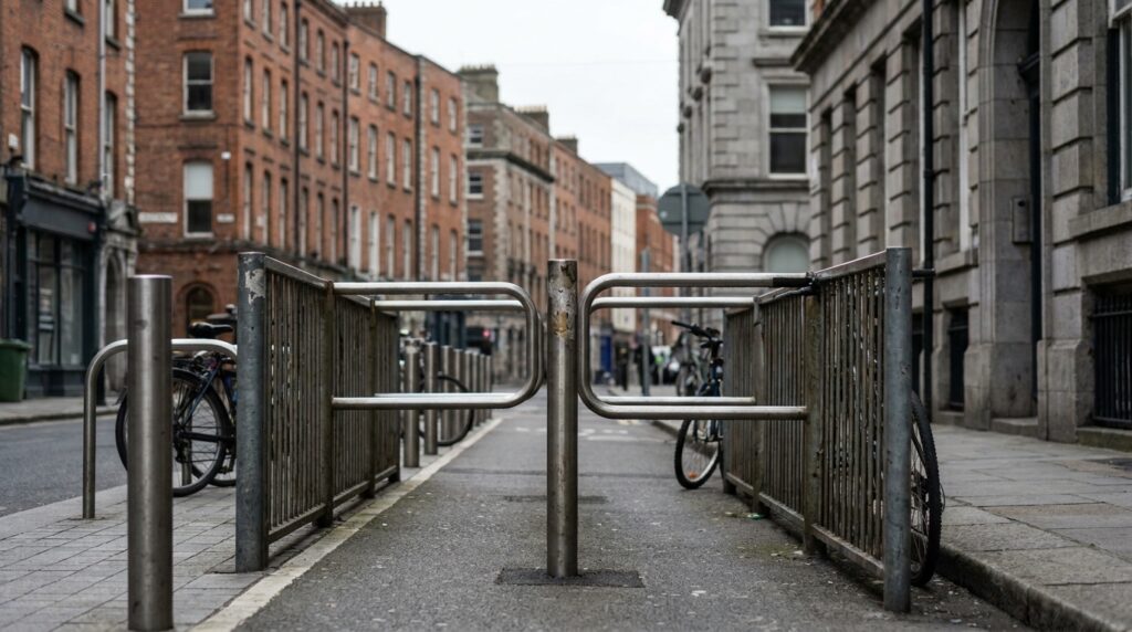 Fotografia realista de uma bicicleta como único protagonista visual diante de uma barreira metálica estreita em uma via compartilhada de Dublin, demonstrando concretamente a dificuldade de passagem causada pela infraestrutura urbana, sem pessoas e sem textos visíveis.
