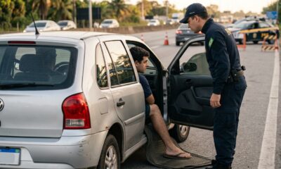 Homem é parado numa blitz dirigindo de chinelo e já se prepara para a multa, mas o agente explica que isso não existe no Código de Trânsito — o que dá multa é o calçado que atrapalha o controle dos pedais