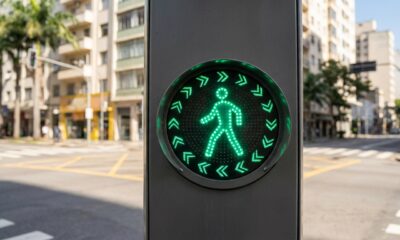 O semáforo com setas verdes ao redor do pedestre que está mudando a travessia nas ruas