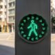 O semáforo com setas verdes ao redor do pedestre que está mudando a travessia nas ruas