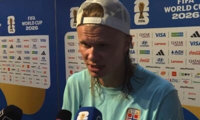 Erling Haaland, de boné branco, camisa azul, fala em painel da Copa do Mundo 2026 e patrocinadores.