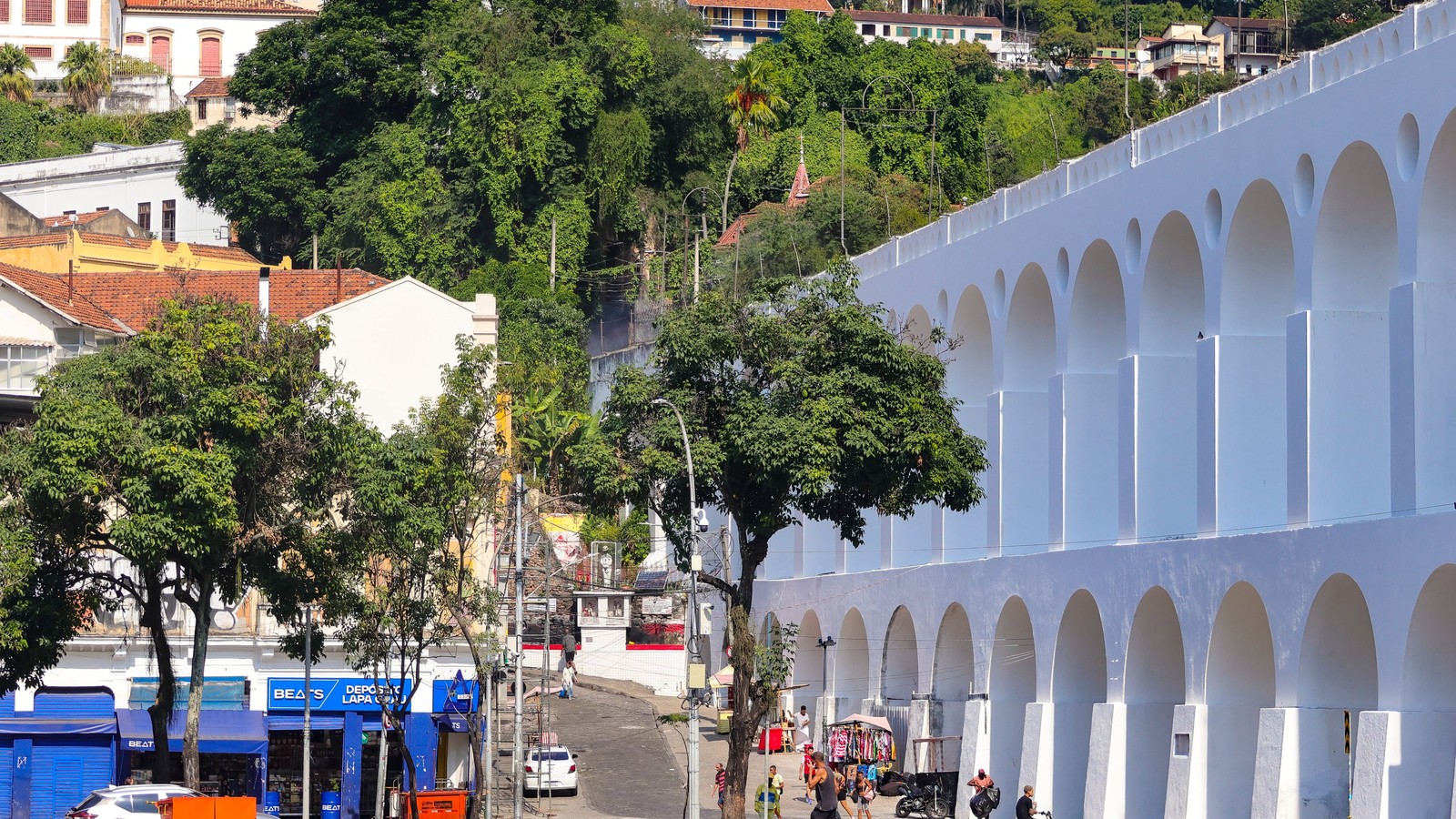Arcos da Lapa brancos e limpos, com rua movimentada e prédios no Rio de Janeiro
