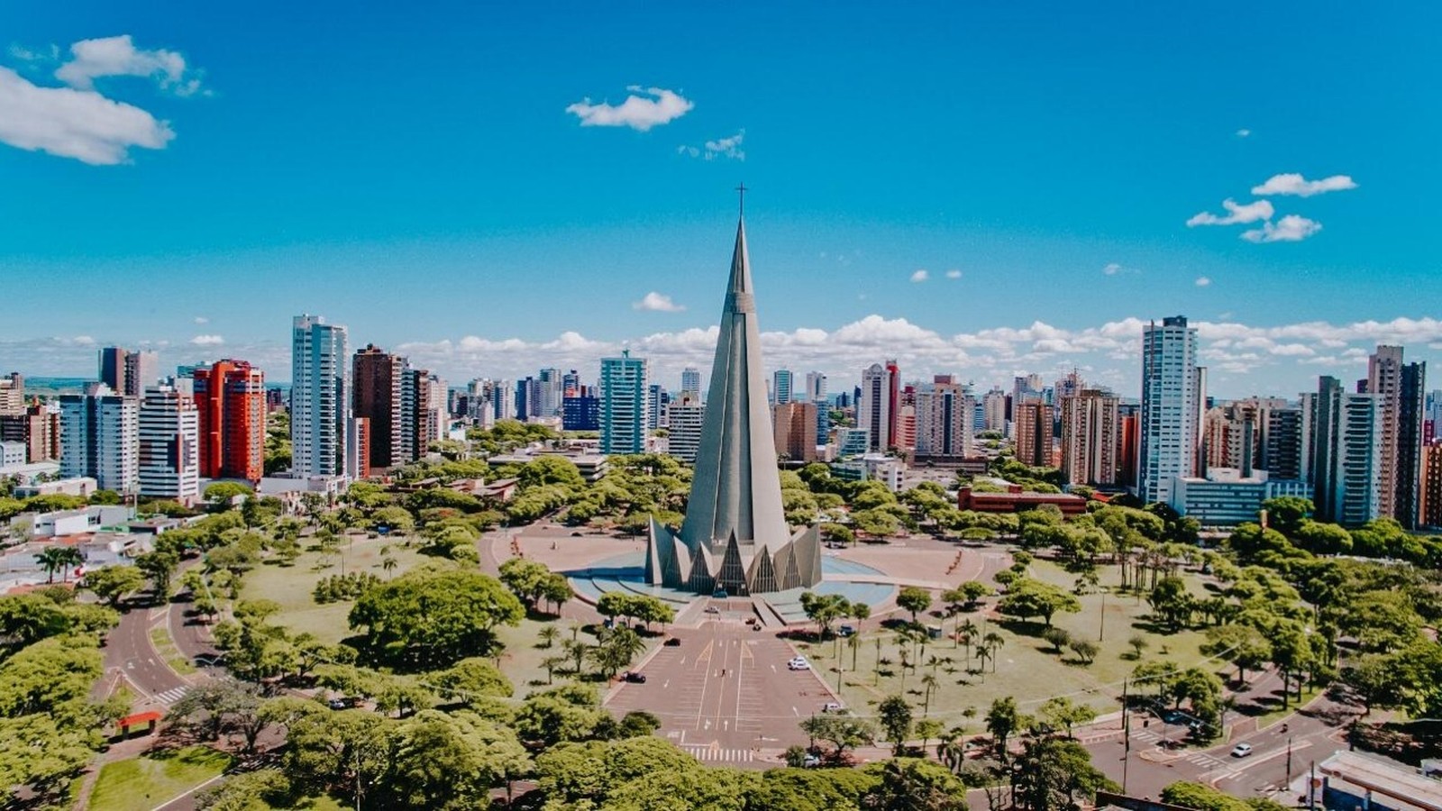 Vista aérea da Catedral de Maringá, estrutura cônica, cercada por área verde e edifícios altos