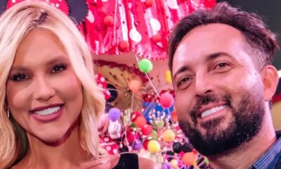 Homem e mulher sorrindo em evento festivo com fundo colorido