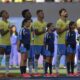 Jogadores de futebol de camisa amarela e crianças mascotes em campo