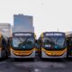 Quatro ônibus BRT novos amarelos e cinzas, com letreiros 'MOBI-RIO' e '54 ANIL'