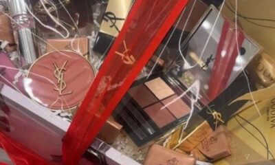 Maquiagens YSL e chocolates Godiva em cesta de presente com fita vermelha
