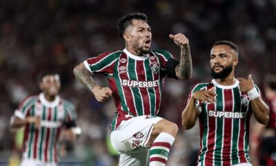 Jogador do Fluminense com barba e tatuagens celebra em campo durante partida noturna