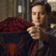 Tobey Maguire segura o traje do Homem-Aranha vermelho e azul, olhando para ele