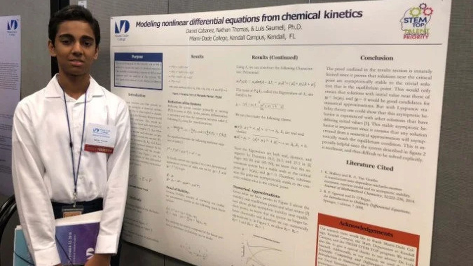 Jovem Nathan Thomas em frente a um pôster científico sobre equações diferenciais na Miami Dade College
