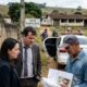 Advogados e homem rural revisam documentos em Sítio Santa Rita, com policial e fotógrafo
