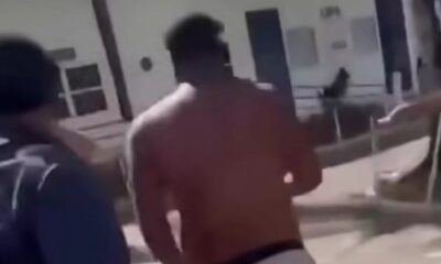 Homem sem camisa e de costas corre em ambiente externo, próximo a edifício, imagem desfocada