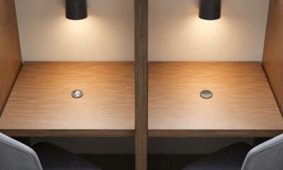 Duas cabines separadas por uma divisória, cada uma com uma moeda sobre a mesa, uma mostrando cara e outra coroa