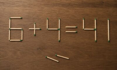 Equação feita com palitos de fósforo sobre mesa de madeira desafia o olhar ao sugerir que apenas dois palitos podem mudar o resultado.