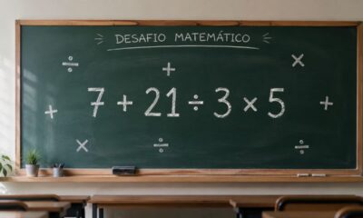 Lousa verde em uma sala de aula com a expressão “7 + 21 ÷ 3 × 5” escrita em destaque e símbolos de adição, divisão e multiplicação ao redor, sem exibir o resultado