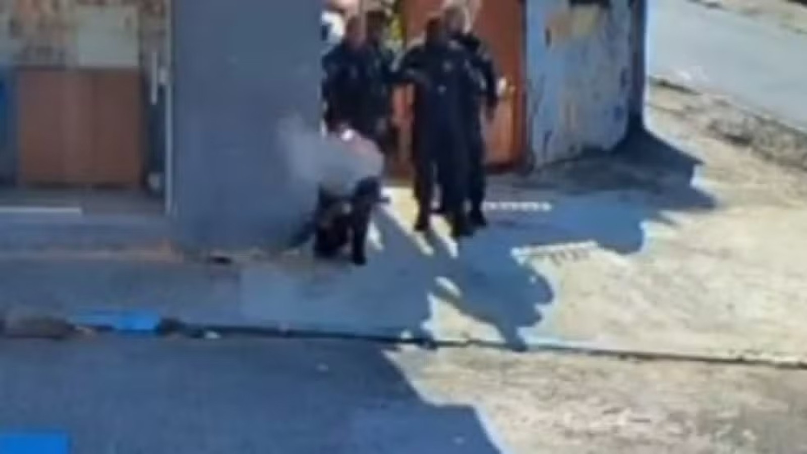 Quatro policiais uniformizados em confronto, um agachado perto de fumaça em Olaria