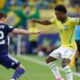 Vini Jr. (camisa 7, Brasil) em ação contra Patterson (camisa 22) em campo de futebol.