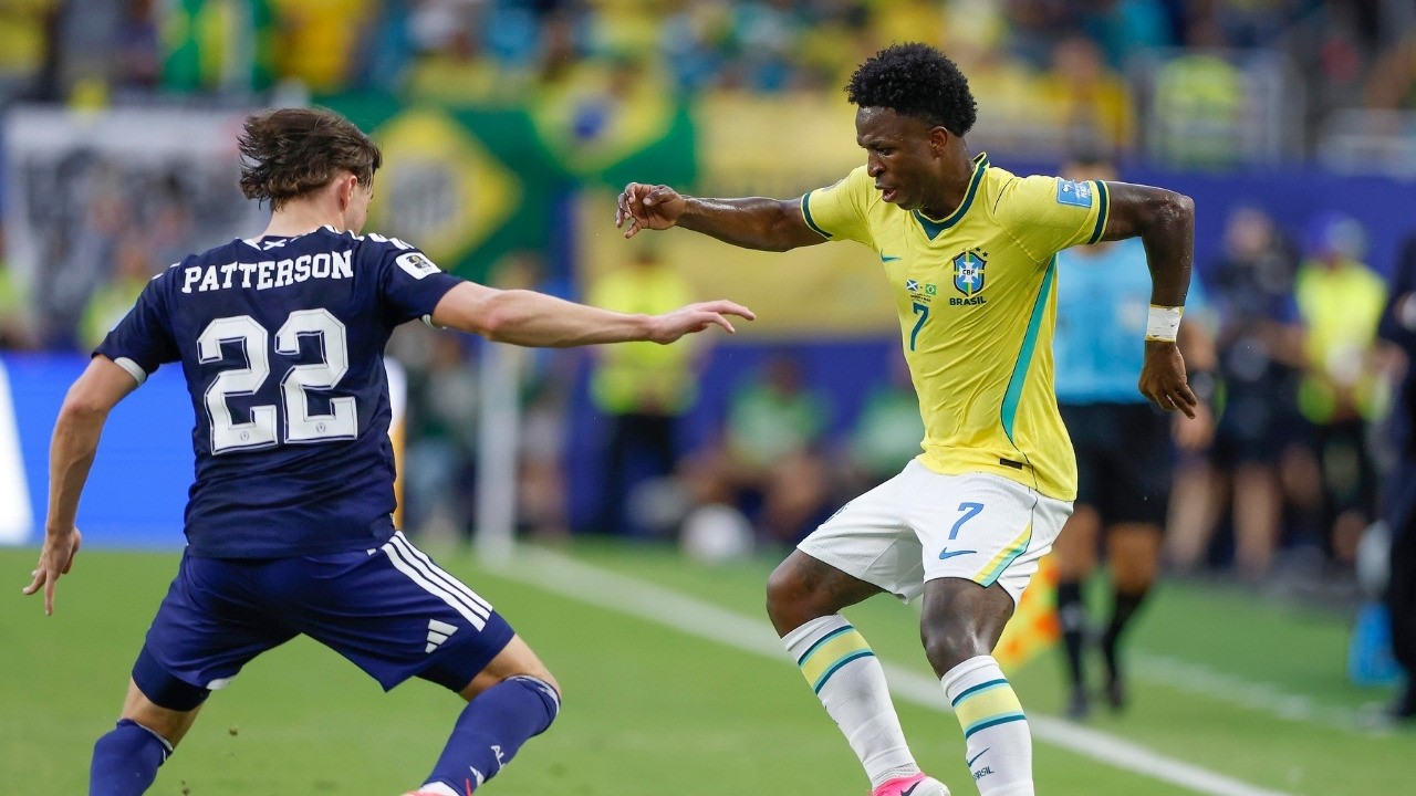 Vini Jr. (camisa 7, Brasil) em ação contra Patterson (camisa 22) em campo de futebol.