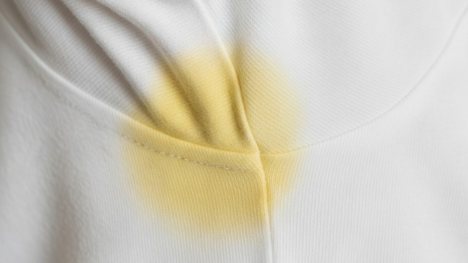 Mancha amarela de desodorante na região da axila de uma camisa branca.