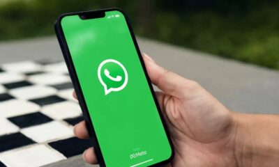 Mão segurando smartphone exibindo a tela inicial do aplicativo WhatsApp com logo e 'from Meta'