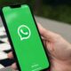 Mão segurando smartphone exibindo a tela inicial do aplicativo WhatsApp com logo e 'from Meta'