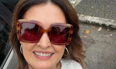 Fátima Bernardes sorrindo, com óculos de sol tartaruga quadrados e brincos de argola
