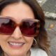 Fátima Bernardes sorrindo, com óculos de sol tartaruga quadrados e brincos de argola