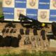 Arsenal com fuzil, pistola, granadas, carregadores e acessórios de drone sobre piso de cerâmica