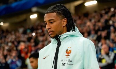 Jogador Michael Olise com dreads, jaqueta azul clara com logotipo da França e patrocinadores