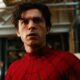 Tom Holland como Homem-Aranha, rosto sério, vestindo traje vermelho e preto em ambiente interno