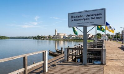 Vista do cais de Tocantinópolis às margens do rio Tocantins, com a cidade e a Catedral de Nossa Senhora da Consolação ao fundo e placa indicando os 168 anos do município