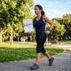 Mulher de aproximadamente 45 anos caminhando rapidamente em um parque enquanto segura um exame com a indicação "Colesterol LDL alto". A cena representa o início de uma rotina de exercícios para ajudar no controle do colesterol.