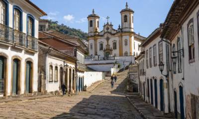 Ladeira de pedra em Ouro Preto levando até uma igreja barroca, cercada por casarões coloniais preservados, com poucos visitantes caminhando em dia ensolarado de inverno em Minas Gerais.