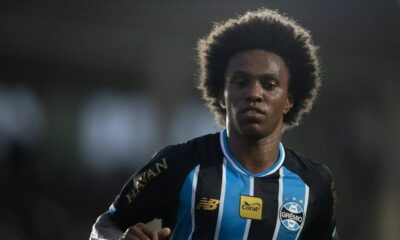 Homem de cabelo crespo e camisa do Grêmio com listras pretas e azuis