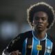 Homem de cabelo crespo e camisa do Grêmio com listras pretas e azuis
