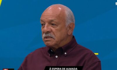 Homem idoso, bigode grisalho, camisa bordô, fundo azul. Logos "SPORTV" e texto "À ESPERA DE ALMADA"