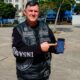 Homem com colete de couro Insanos MC aponta para smartphone com aplicativo na tela
