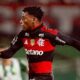 Jogador Gonzalo Plata em campo, camisa Flamengo preta e vermelha, logos, bandagem branca no pulso