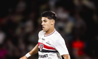 Jogador jovem com camisa branca do São Paulo, logotipo SPFC visível, em campo